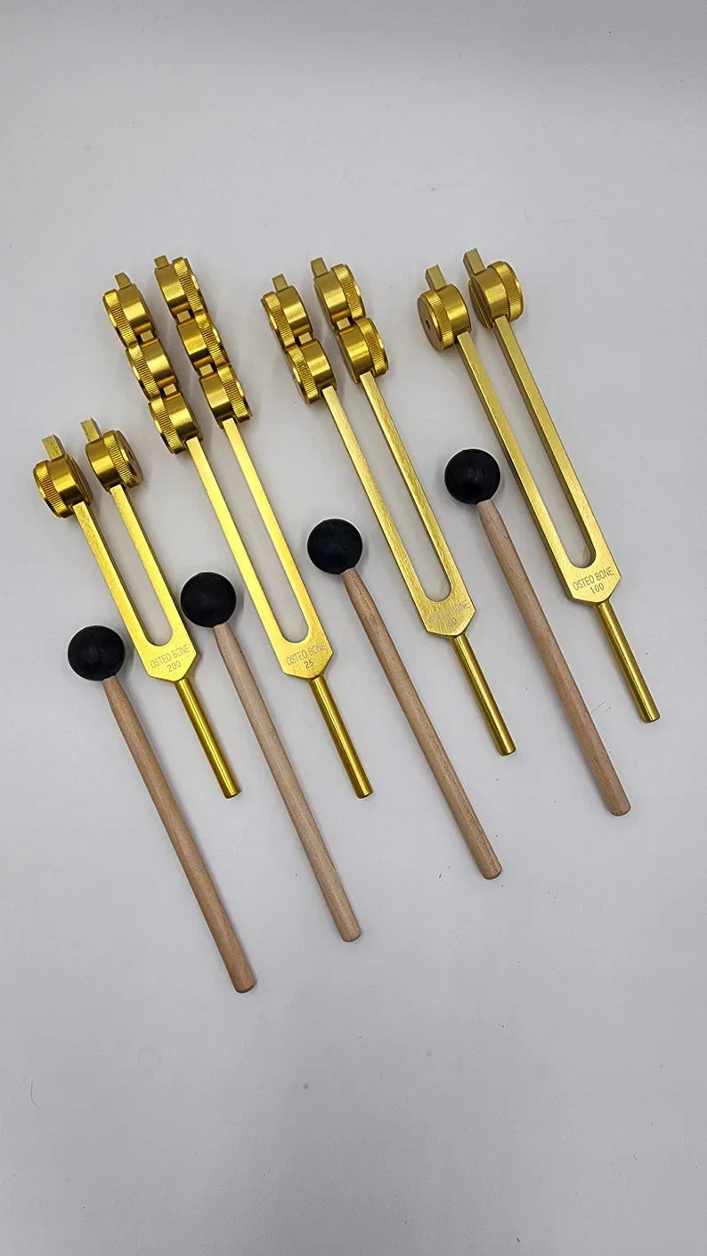 Golden tuning forks with black rubber dampers in a Weighted Osteo Tuning Fork Set of 4